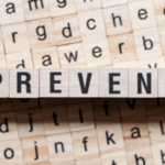 Scrabble tiles spelling "PREVENT" on a background of mixed letters, emphasizing the importance of preventive measures in home safety and HVAC maintenance.