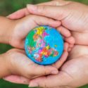 Two hands holding a colorful globe, representing care for the planet, relevant to City Plumbing's environmental initiatives.
