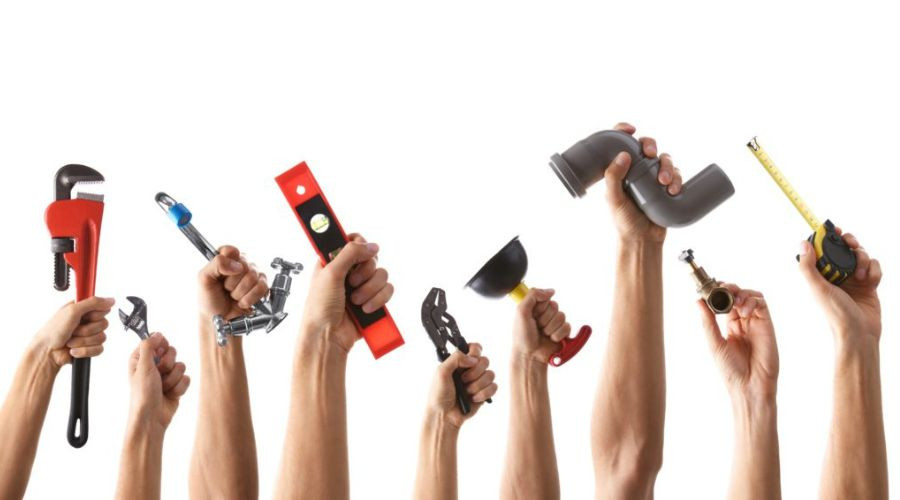 Human hands holding plumbing tools like a wrench and level for commercial plumbing maintenance by City Plumbing.