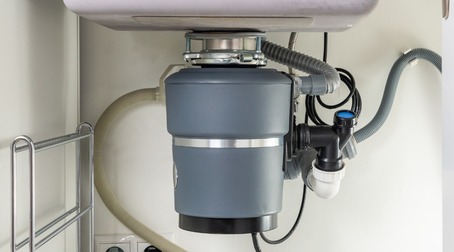 Garbage disposal unit installed under kitchen sink, showcasing plumbing connections and maintenance features for effective waste management.